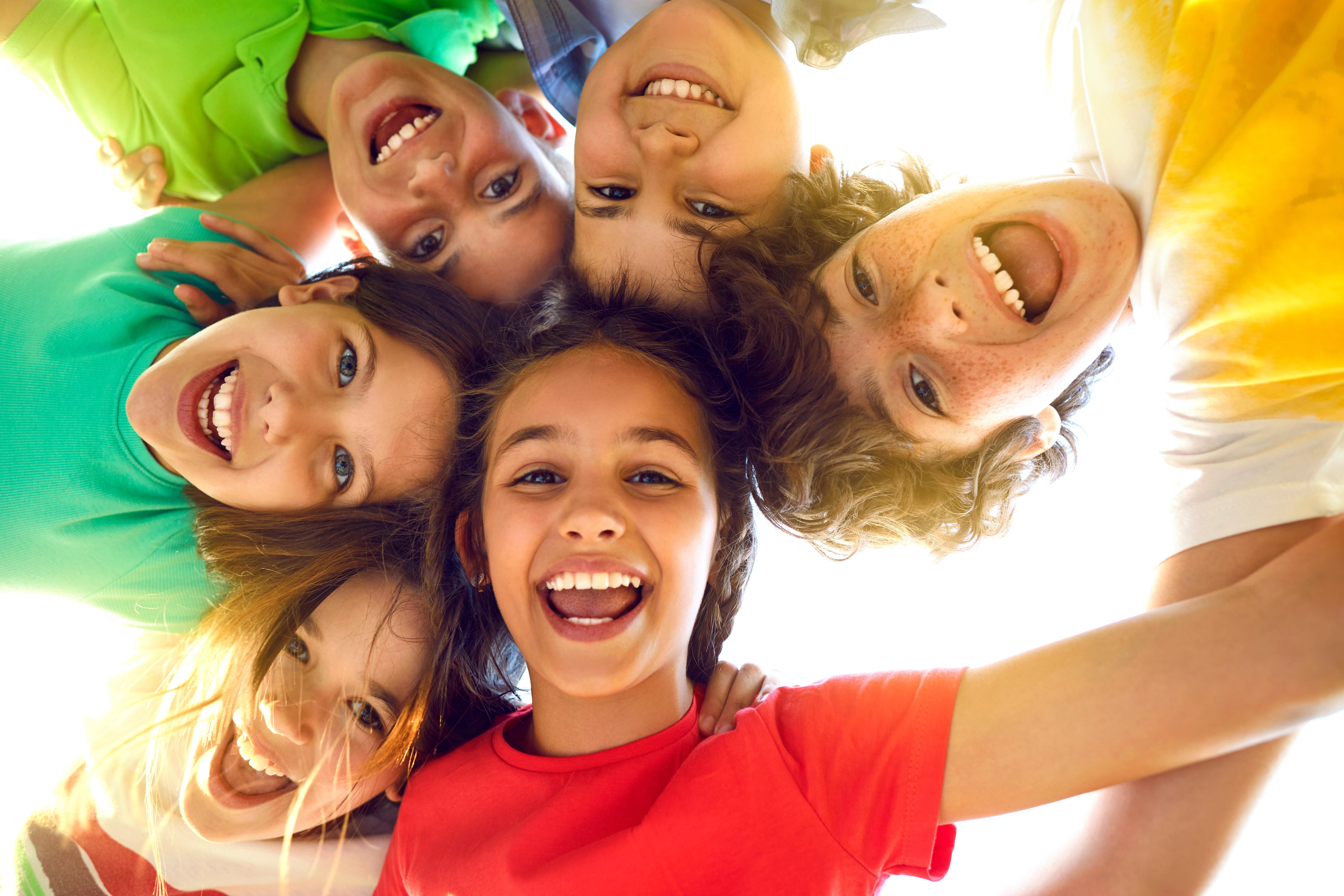 Group of happy little children playing together, having fun, huddling, looking down and smiling