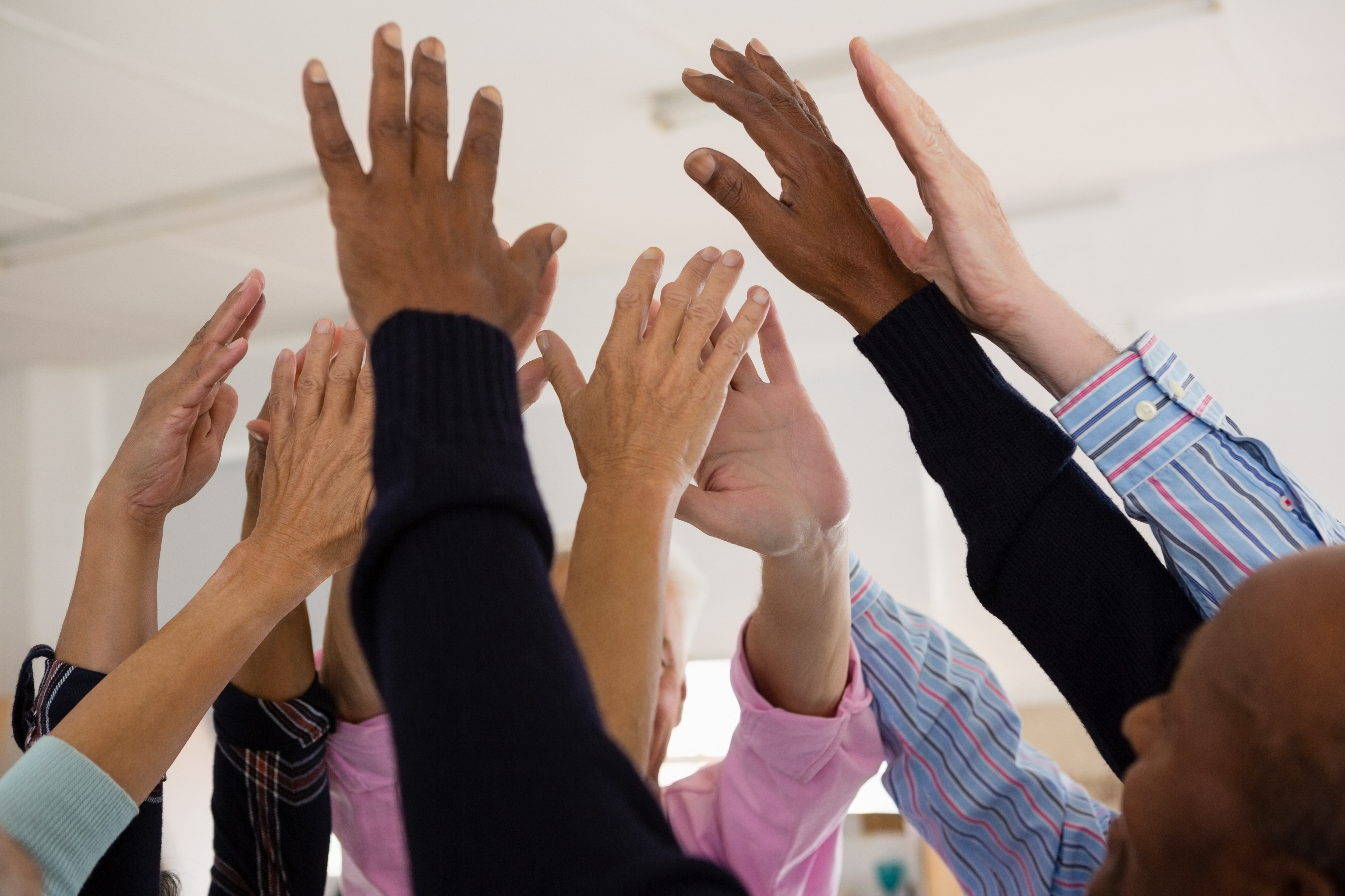 Close up of senior friends with arms raised in art class