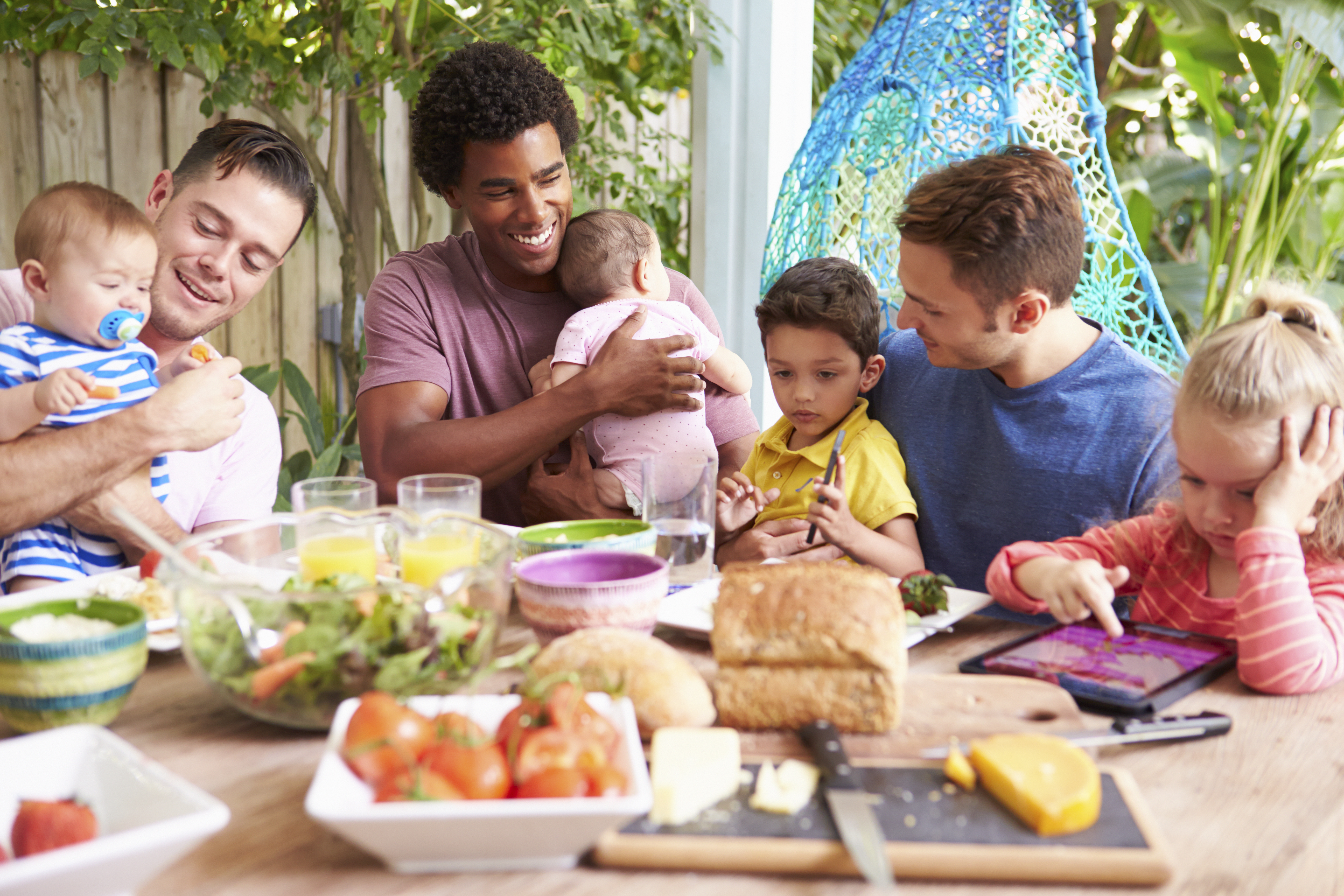 Group Of Fathers With Children Enjoying Outdoor Meal At Home